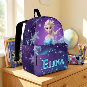May include: A purple backpack featuring a graphic of a blonde character in a blue dress, surrounded by white snowflakes and stars. The front pocket displays the name ELINA in large, light blue letters with a white outline against a dark background.