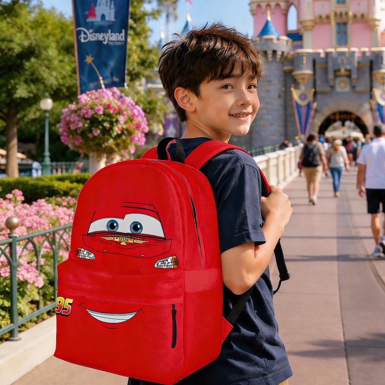 Puede incluir: Una mochila roja con la cara de Rayo McQueen de la pel&iacute;cula Cars de Disney Pixar. La mochila tiene un bolsillo frontal grande y correas negras. El n&uacute;mero "95" es visible en el lateral. La mochila la lleva una persona.