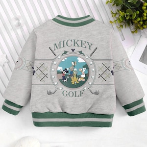 May include: A grey and green baseball jacket with a Mickey Mouse golf theme. The jacket features a large graphic of Mickey Mouse, Goofy, Donald Duck, and Pluto playing golf. The text "Mickey Golf" is printed on the jacket.