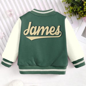 May include: Green and white baseball style jacket with the name "James" in a vintage style font on the back.