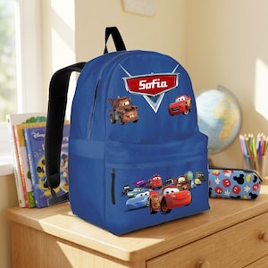 May include: A blue backpack decorated with characters from the Cars movie, such as Lightning McQueen and Mater. The backpack has a zip pocket and the name "Sofia" on a red and white emblem. It features a black handle and straps.