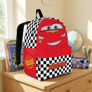 Peut inclure: Un sac &agrave; dos rouge avec Flash McQueen du film Cars. Le sac &agrave; dos pr&eacute;sente un motif &agrave; carreaux noir et blanc sur les c&ocirc;t&eacute;s et une grande image du personnage sur le devant. Le mot "SOFIA" est imprim&eacute; sur la poche avant.