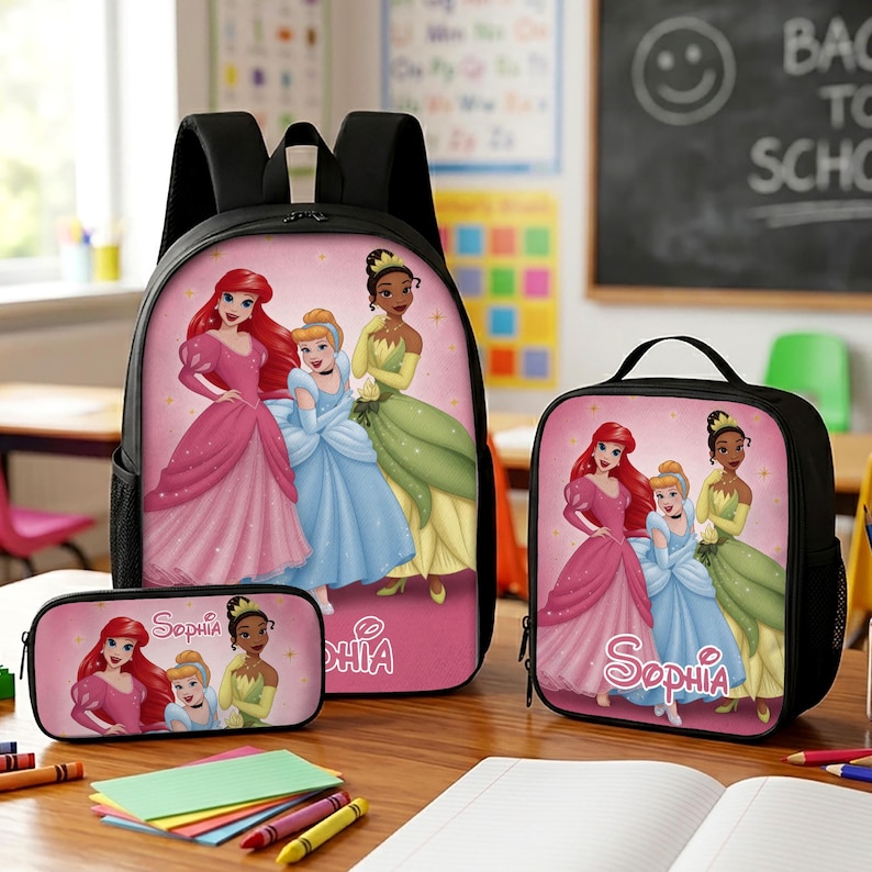 May include: A black backpack, lunch bag, and pencil case set featuring a pink background with illustrations of Ariel, Cinderella, and Tiana. The name Sophia is printed in white script on the pencil case and lunch bag, with a pink graphic design.