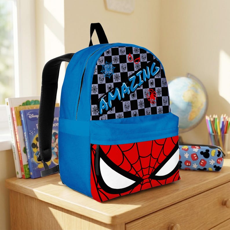 May include: A blue backpack featuring a Spider-Man design. The backpack has a red and black spiderweb design on the front, with the word "AMAZING" in blue. The top section has a checkered pattern with spider icons.