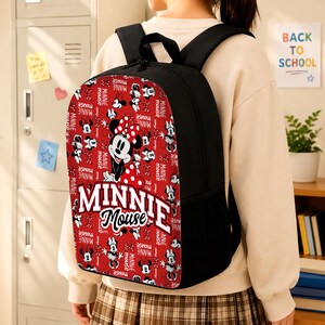Pu&ograve; includere: Uno zaino nero con un pannello frontale rosso caratterizzato da una stampa all-over di personaggi di Minnie Mouse, fiocchi a pois e la scritta Minnie Mouse in grandi lettere bianche. Lo zaino ha spallacci neri e tasche laterali in rete.