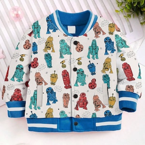 May include: A white and blue bomber jacket with a colorful cartoon pattern of robots and the word "beep" repeated throughout. The jacket has a blue collar and cuffs, and a white zipper.