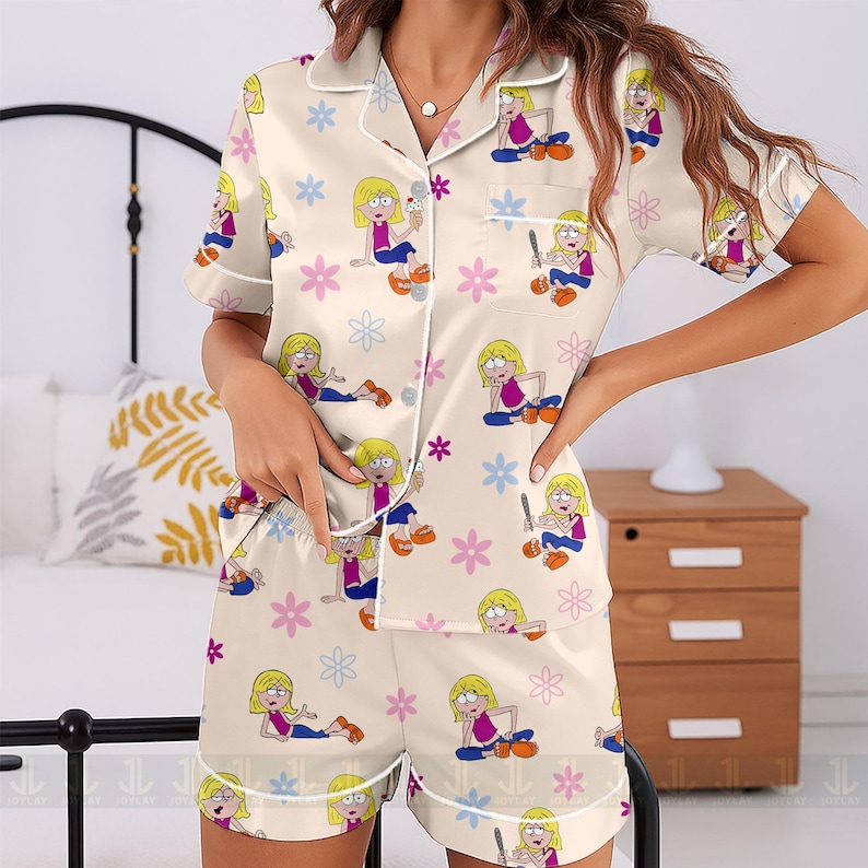 Pu&ograve; includere: Pigiama color crema con stampa di personaggi dei cartoni animati e accenti floreali. La maglia a maniche corte e i pantaloncini sono adornati da un motivo ripetuto di una ragazza bionda, fiori e stelle. Le bordature bianche rifiniscono il completo.