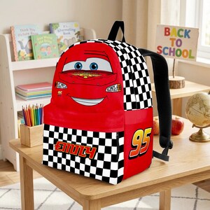 Peut inclure: Sac &agrave; dos rouge Lightning McQueen avec un motif &agrave; carreaux noir et blanc. Le sac &agrave; dos porte le num&eacute;ro 95 et le nom "Emily". Il a des bretelles noires et une poign&eacute;e sup&eacute;rieure. Un sac &agrave; dos amusant et color&eacute; pour l'&eacute;cole.