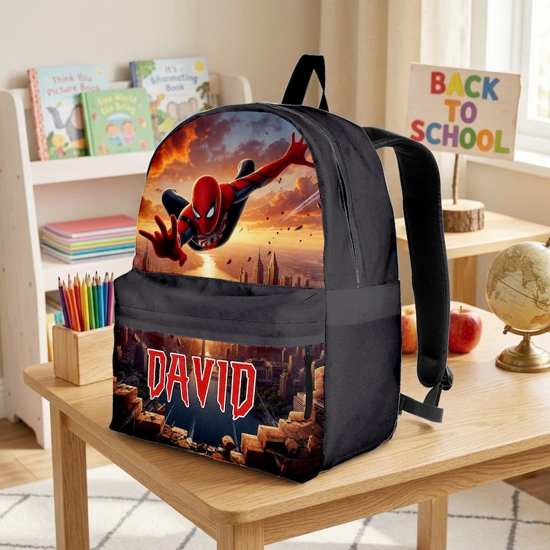 May include: A black backpack featuring a graphic of Spider-Man leaping through the air against a sunset city skyline. The front pocket displays the name DAVID in bold red letters over a cityscape with crumbling brick elements at the bottom.