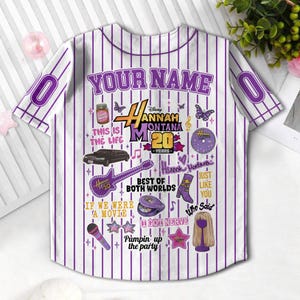 May include: White and purple pinstripe baseball jersey with the text "YOUR NAME" at the top. The jersey features various graphics and text related to Hannah Montana, including "Hannah Montana 20 Years".