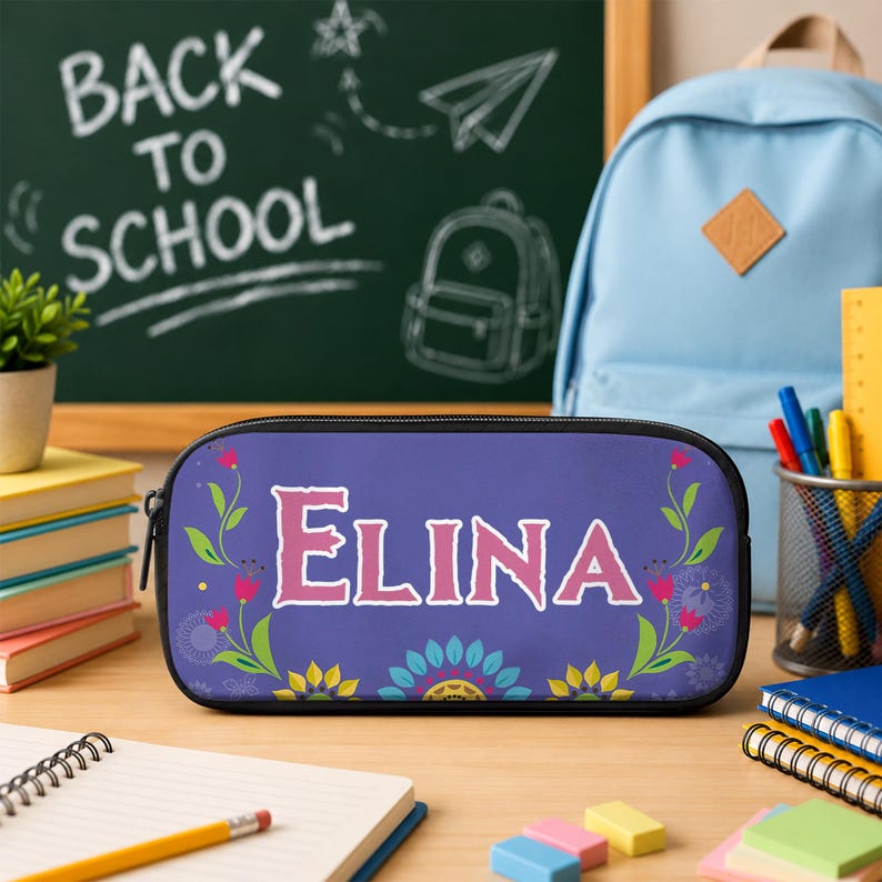 Op de afbeelding: Een rechthoekig paars etui met de naam ELINA in grote roze letters, omringd door groene ranken met roze bloemen en een kleurrijk bloemenpatroon aan de onderkant. Het etui heeft een zwarte rits en een zwarte rand langs de zijkanten.