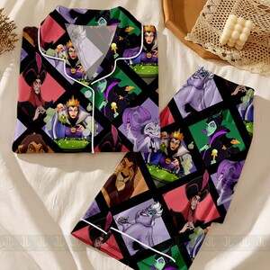 May include: A two-piece pajama set featuring a colorful geometric pattern with various Disney villains. The long-sleeved top and pants are black with white trim and a button-down front. The design includes images of Ursula, Maleficent, and the Evil Queen.