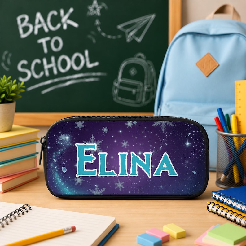 May include: A rectangular pencil case with a dark purple, starry night sky background featuring white snowflake patterns and the name ELINA printed in large, light blue, stylized capital letters across the center of the front panel.