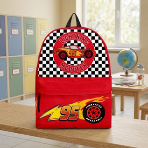 May include: Red backpack featuring Lightning McQueen from the Cars movie. The top section has a black and white checkered pattern with a circular image of the car and the text "LIGHTNING MCQUEEN 95". The bottom section has a yellow and red graphic with the number "95".