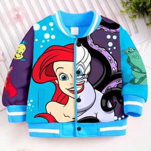 May include: A blue and purple baseball jacket with a graphic print of Ariel and Ursula from The Little Mermaid. The jacket has a zipper closure and white stripes on the sleeves.
