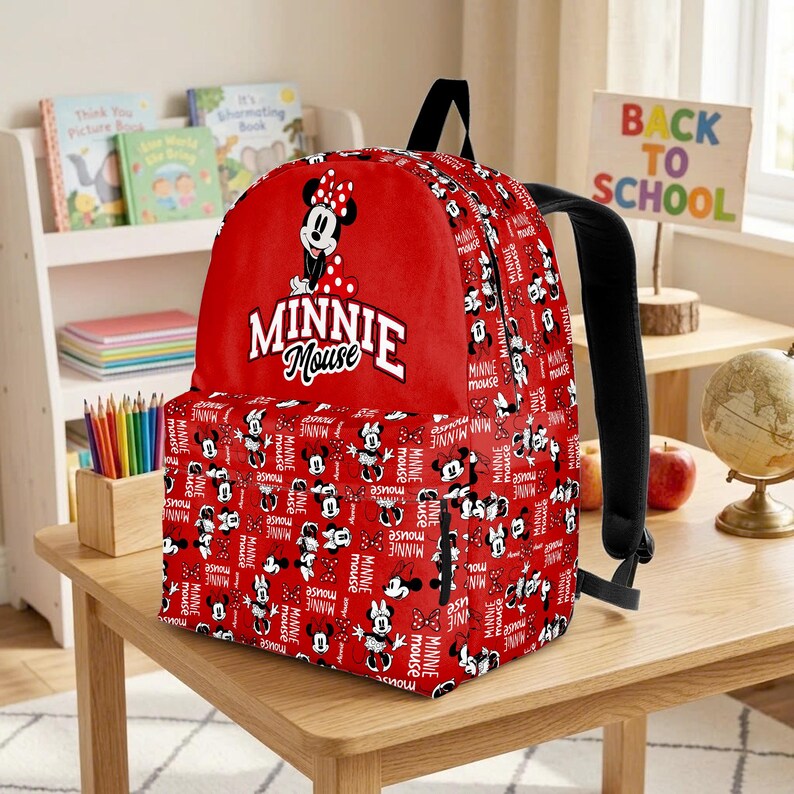 May include: Red Minnie Mouse backpack with a black handle and straps. The backpack features a large Minnie Mouse graphic and the words "MINNIE MOUSE". The body of the backpack is covered in a pattern of Minnie Mouse images and the words "MINNIE MOUSE".