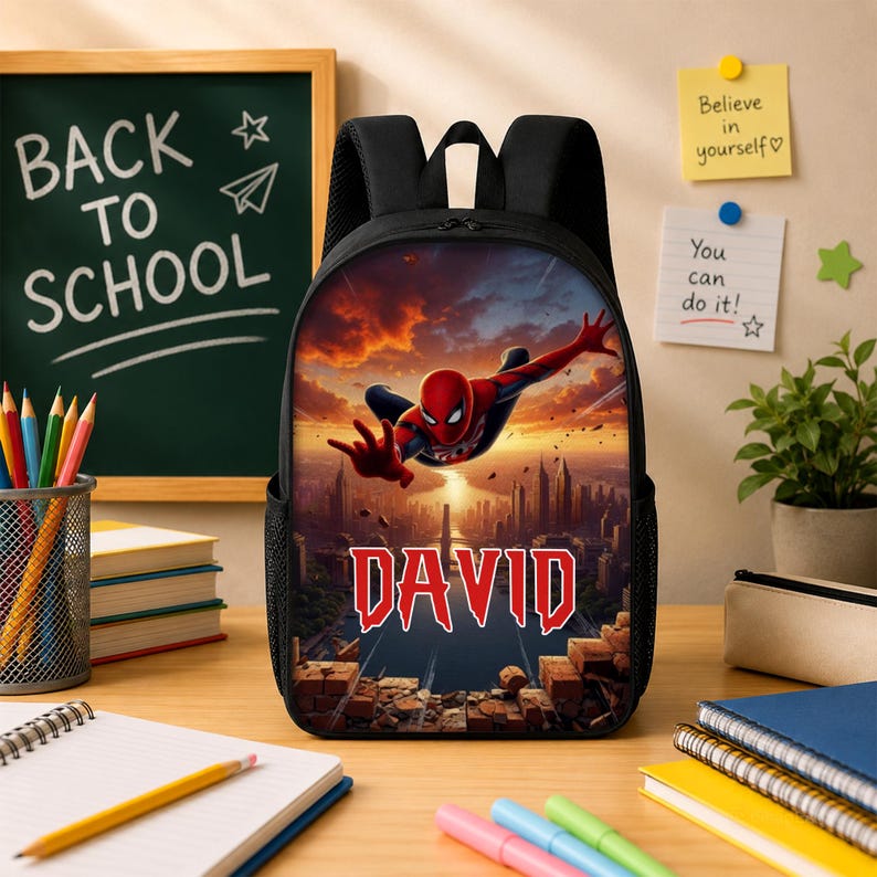 May include: A black backpack featuring a graphic print of the superhero Spider-Man leaping over a city skyline at sunset. The name DAVID is printed in large, bold red letters below the character. The bag has black straps and side mesh pockets.
