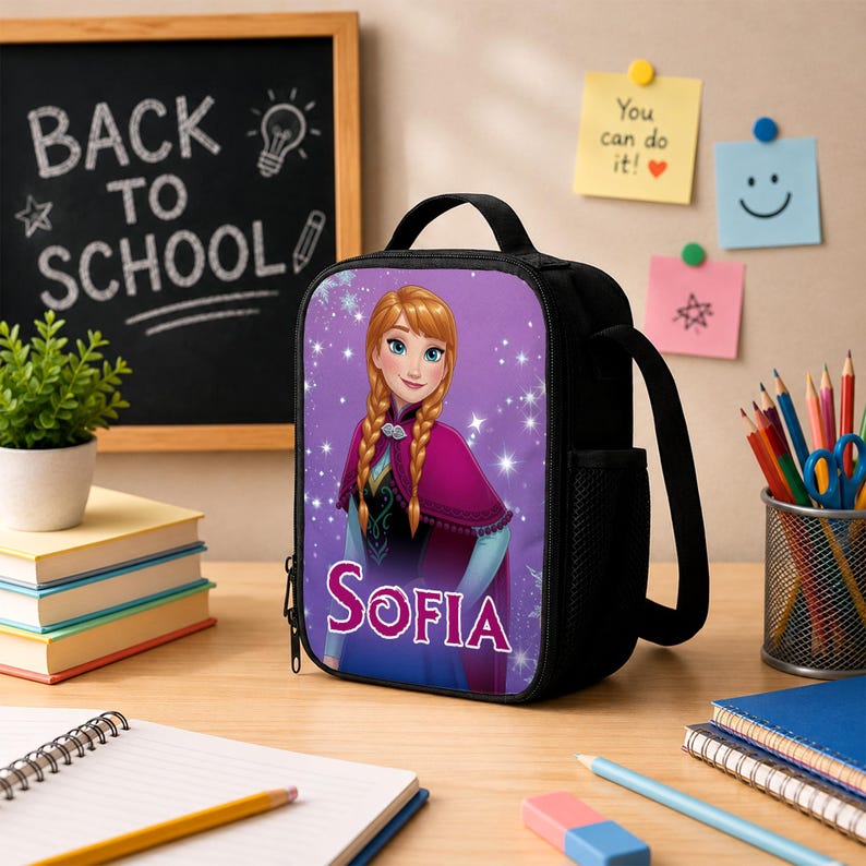 Pu&ograve; includere: Una borsa termica nera con la stampa di un personaggio dai capelli biondi intrecciati che indossa un mantello magenta e un abito blu, con il nome Sofia stampato in lettere bianche sotto il personaggio su uno sfondo viola con scintille bianche.