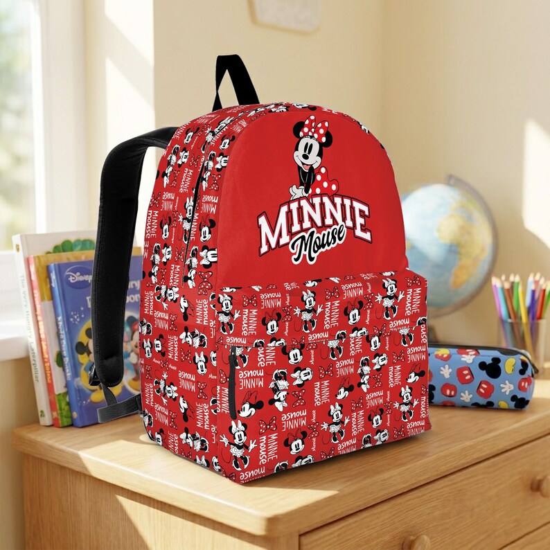 May include: Red Minnie Mouse backpack with black straps. The backpack features a large Minnie Mouse graphic and the words "Minnie Mouse" in white. The main body of the backpack is covered in a pattern of Minnie Mouse illustrations and the words "Minnie Mouse".