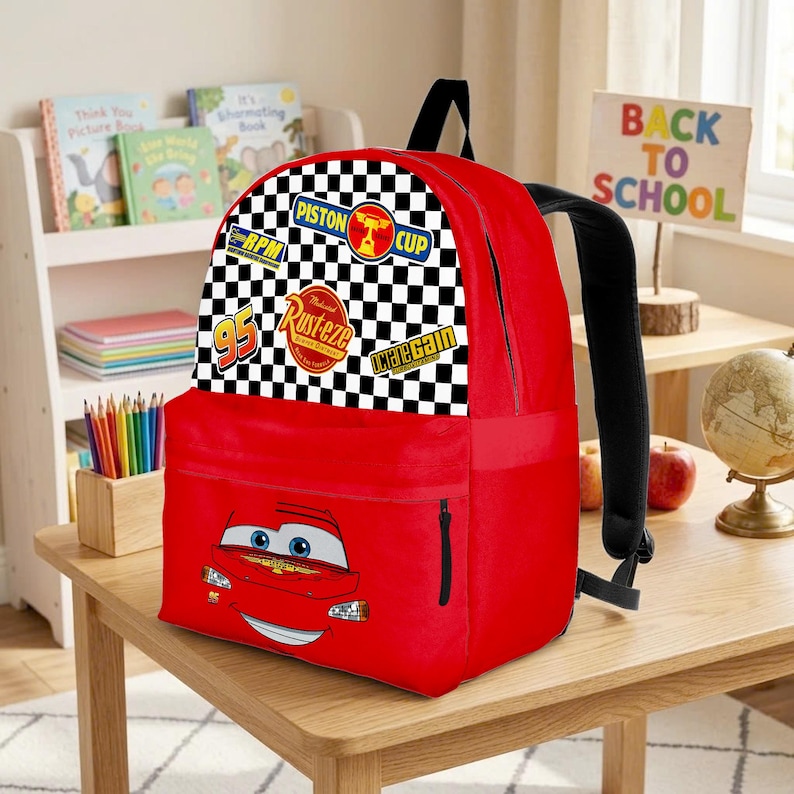 May include: Red backpack with a cartoon car design, a checkered flag pattern, and racing logos. It has a black handle and straps, plus a zipped front pocket. The words "Back to School" are visible in the background.