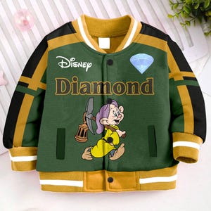 May include: A green and yellow baseball jacket with a Disney Diamond logo and a cartoon image of a dwarf holding a pickaxe. The jacket has a white collar and a zipper closure.