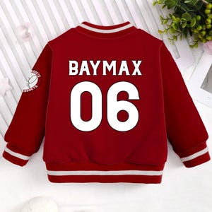 May include: Red baseball jacket with white stripes on the sleeves and bottom hem. The back of the jacket has a white graphic with the text "BAYMAX 06".