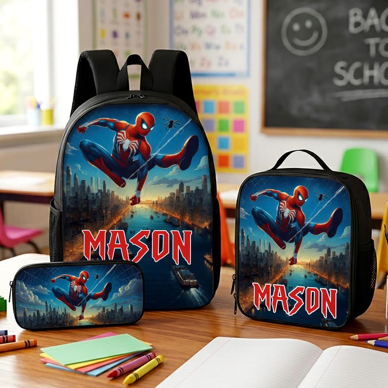 Puede incluir: Un conjunto de mochila, bolsa de almuerzo y estuche negros con un gr&aacute;fico de Spider-Man sobre un paisaje urbano. Cada art&iacute;culo muestra el nombre MASON en letras rojas. El conjunto incluye correas negras y bolsillos laterales de malla.