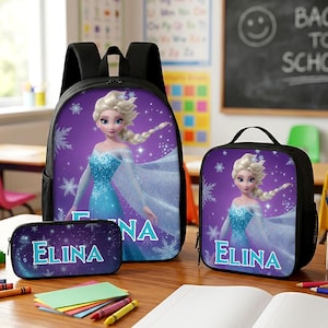 May include: A black backpack, lunch bag, and pencil case set featuring a purple background with a graphic of a blonde character in a blue dress and the name ELINA printed in light blue letters, surrounded by white snowflake patterns.