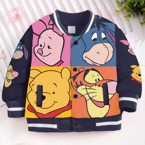 May include: A blue, white, and yellow baseball jacket with a colorful patchwork design featuring Winnie the Pooh, Tigger, Piglet, and Eeyore.