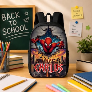 May include: A black backpack featuring a graphic print of a red and blue superhero bursting through a brick wall above a city skyline. The name CARLOS is printed in large red letters at the bottom of the design. The bag has black straps and mesh sides.