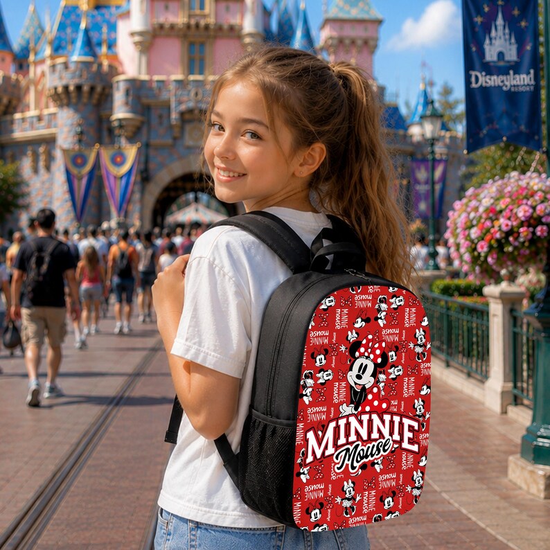 Pu&ograve; includere: Uno zaino nero con un motivo rosso all-over di volti e fiocchi di Minnie Mouse, caratterizzato da una grande grafica centrale di Minnie Mouse e dalla scritta bianca "MINNIE MOUSE" stampata sulla tasca anteriore. Lo zaino ha spallacci neri.