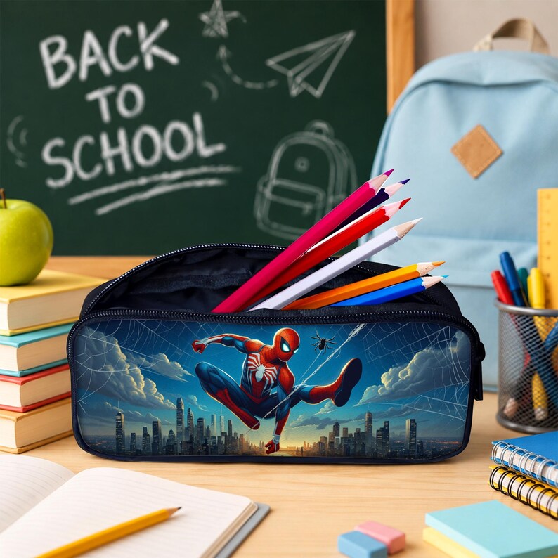 Puede incluir: Un estuche de l&aacute;pices azul oscuro con un gr&aacute;fico de Spider-Man con traje rojo y azul sobre el horizonte de una ciudad. El estuche est&aacute; abierto y muestra varios l&aacute;pices de colores rojo, blanco, amarillo y azul guardados en su interior.