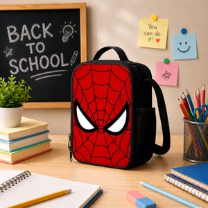 May include: A rectangular black lunch bag featuring a red front panel with a black spiderweb pattern and two large white eyes. The bag has a top handle, a side mesh pocket, and a zipper closure. The design is inspired by a comic book character.