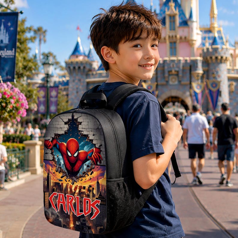 May include: A black backpack featuring a graphic print of the superhero Spider-Man emerging from a brick wall above a city skyline. The name Carlos is printed in large, stylized red letters at the bottom of the backpack design.