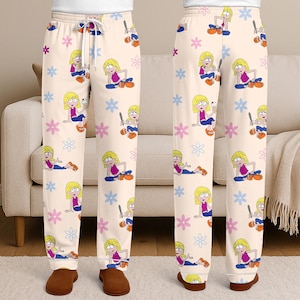 Pu&ograve; includere: Pantaloni da pigiama color crema con un motivo ripetuto di una ragazza dei cartoni animati, fiori e mazze da baseball. La ragazza &egrave; raffigurata con capelli biondi, un top rosa, jeans blu e scarpe marroni. I pantaloni hanno un girovita con coulisse.