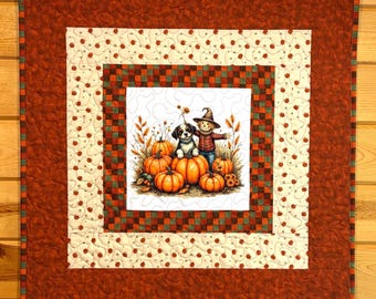 Può includere: Un arazzo quadrato in tessuto con un'illustrazione centrale di un cucciolo e uno spaventapasseri circondati da zucche arancioni. La trapunta presenta un bordo color crema con piccoli motivi a zucca e una cornice interna a scacchi.