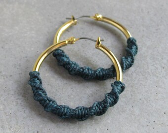 Aros gruesos de oro con detalle de fibra de macramé en color verde esmeralda. Joyería bohemia moderna.