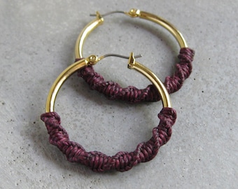 Aros gruesos dorados con detalle de fibra de macramé en color burdeos. Joyería bohemia moderna y chic.
