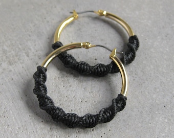 Aros dorados gruesos con detalle de fibra de macramé en negro. Joyería bohemia moderna y chic.