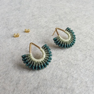May include: A pair of teardrop-shaped earrings with a gold wire frame and a green and white macrame design.