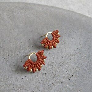 Peut inclure: Une paire de petites boucles d'oreilles rouges en perles avec des anneaux dorés. Les boucles d'oreilles ont la forme d'un éventail.