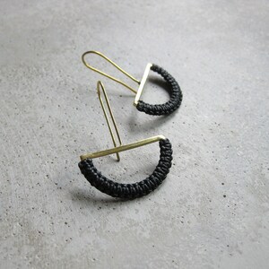 Peut inclure: Une paire de boucles d'oreilles en or avec un cordon noir enroulé autour d'une demi-lune.