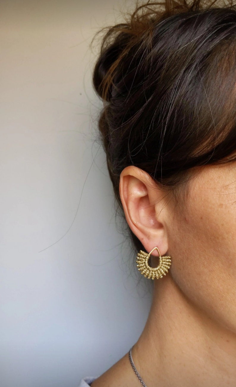 A pair of small fan shaped stud earrings featuring a handwoven metallic gold thread detail done by micro macrame technique on a 16 carat gold plated teardrop shape stud earrings.