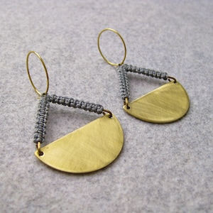 May include: A pair of gold earrings with a half-circle shape and gray cord accents.
