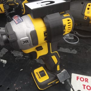 Può includere: Un trapano DeWalt giallo e nero con un attacco magnetico in cima. Il trapano ha una batteria nera e un cavo nero attaccato ad esso. Il trapano è seduto su una superficie nera con un cartello bianco che dice "FOR TO FOR".