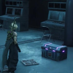 May include: A gray metal chest with a purple glow around the edges. The chest is sitting on a gray floor in a room with a dark gray wall.