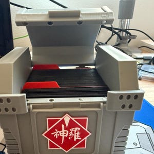 May include: A gray plastic storage box with a hinged lid. The box is open and contains a stack of black cards with red dividers. The box has a red and white logo with the text "神護" on the front.