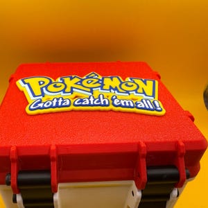 May include: Red and white Pokemon trading card game storage box with a yellow and blue Pokemon logo and the text "Gotta catch 'em all!"