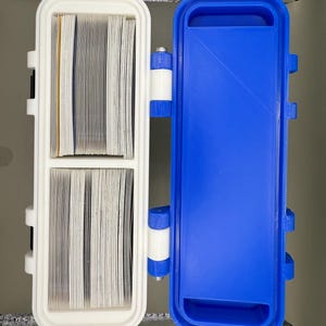 May include: A white plastic case with two compartments, one for storing cards and the other empty. The case is hinged and has a blue plastic lid.