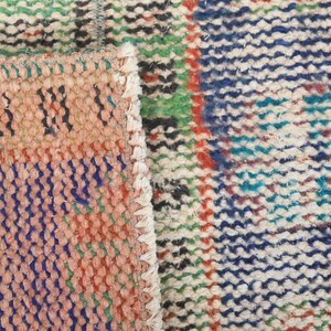 May include: Close-up of a colorful woven rug with a variety of colors, including red, blue, green, and white. The rug has a textured surface and is made of a thick, durable material.